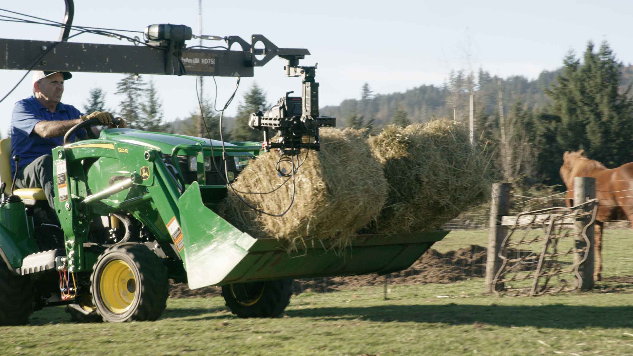 John Deere tractor carrying hay bale on jib shot