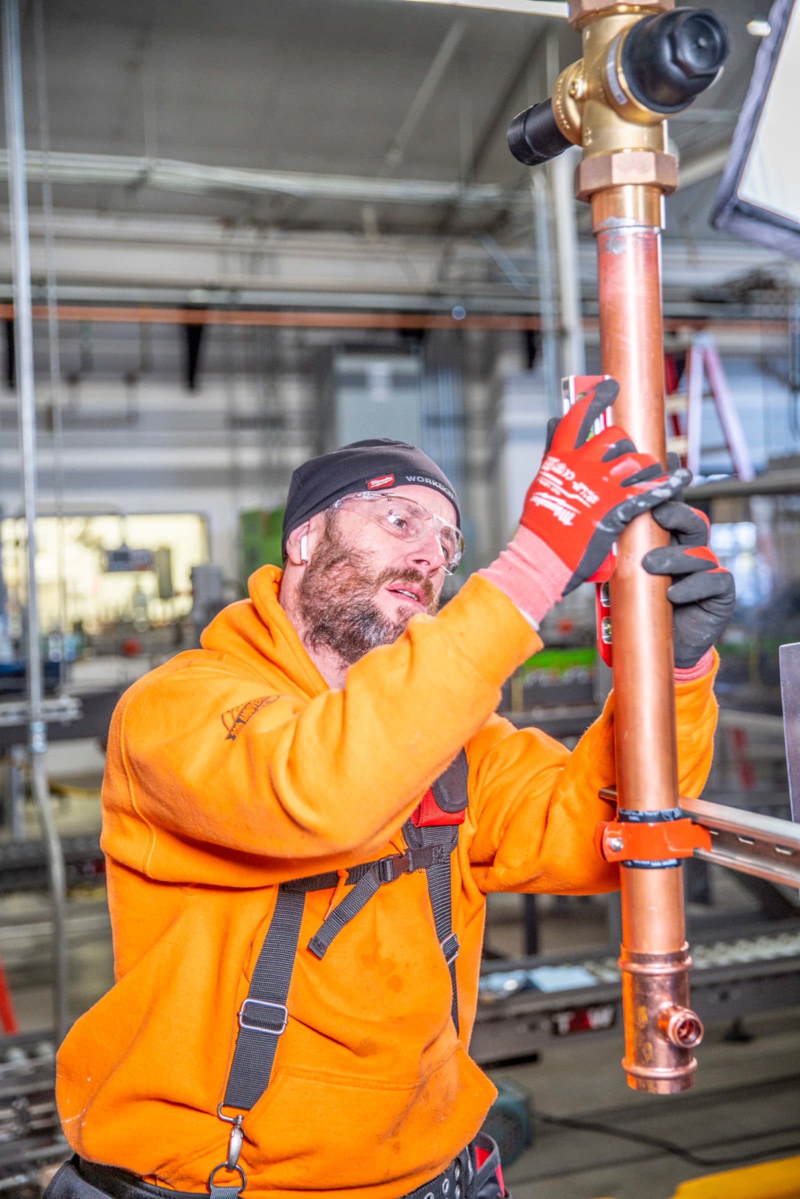 Plumber holding copper pipe with red valve