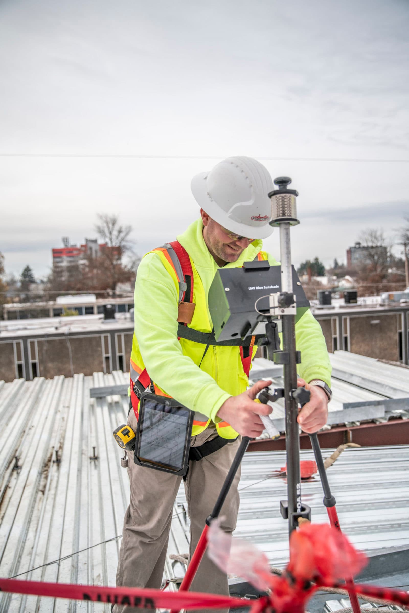 Surveyor with GPS rover on roof (portrait)