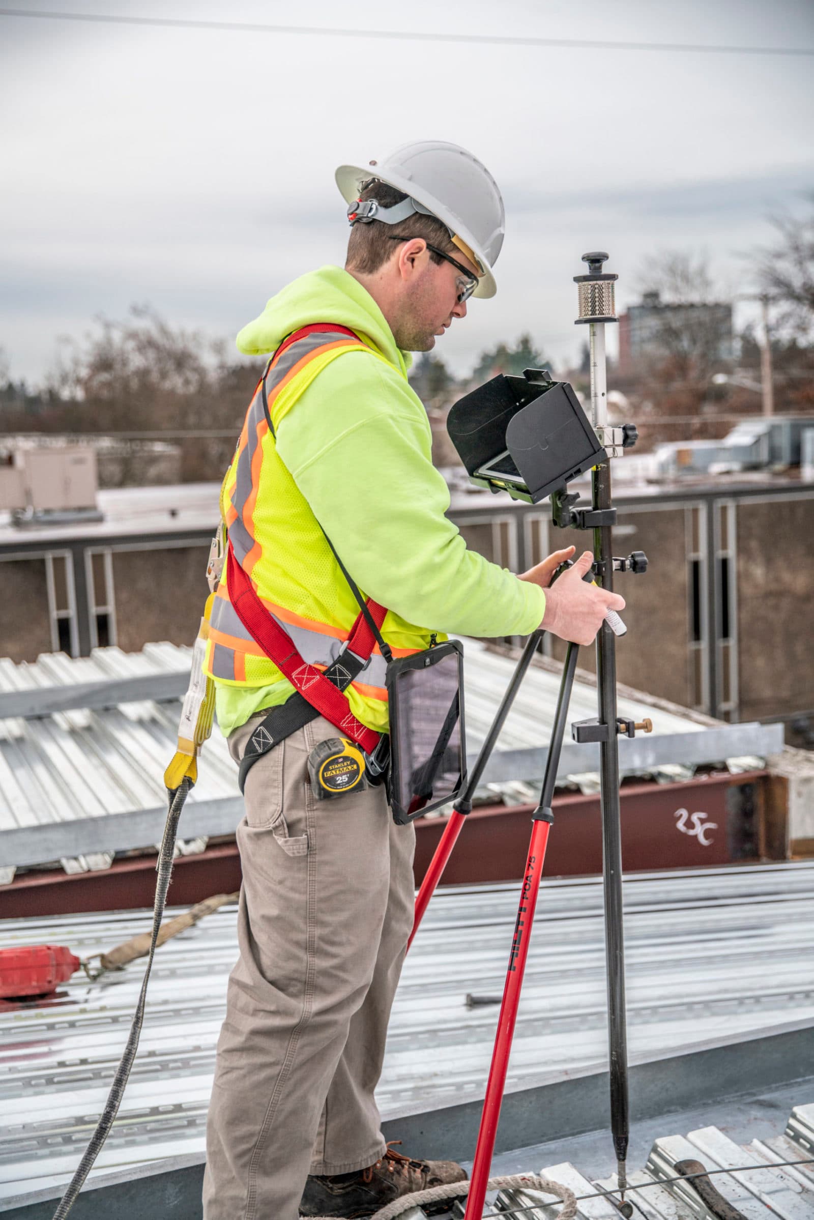 Surveyor with GPS rover pole on roof (portrait)