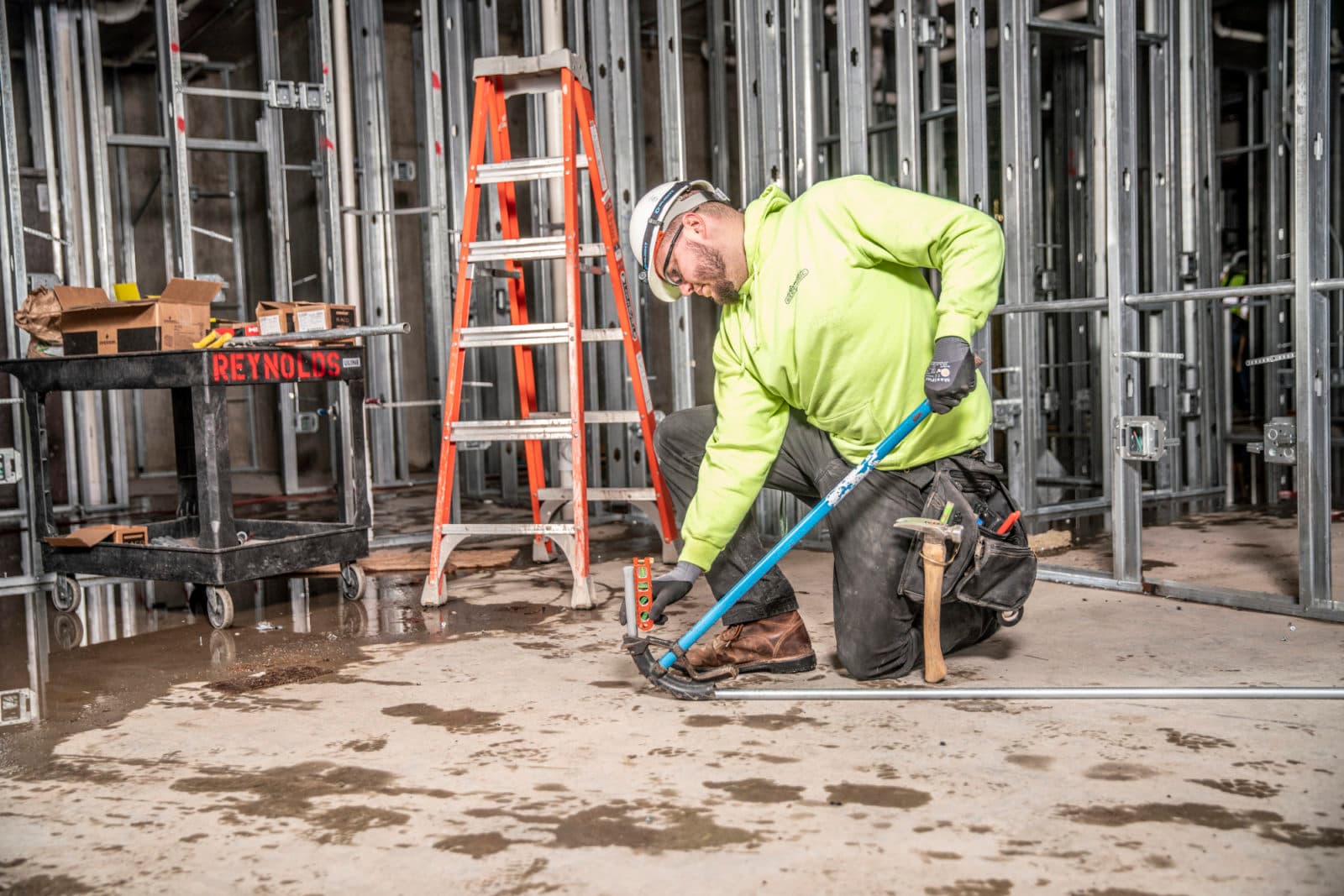 Worker kneeling with tool on wet concrete floor