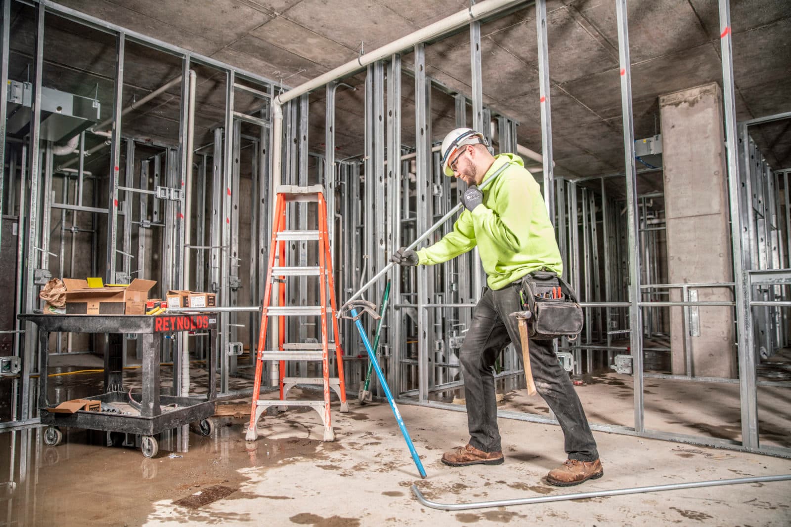 Electrician working in framed interior with ladder