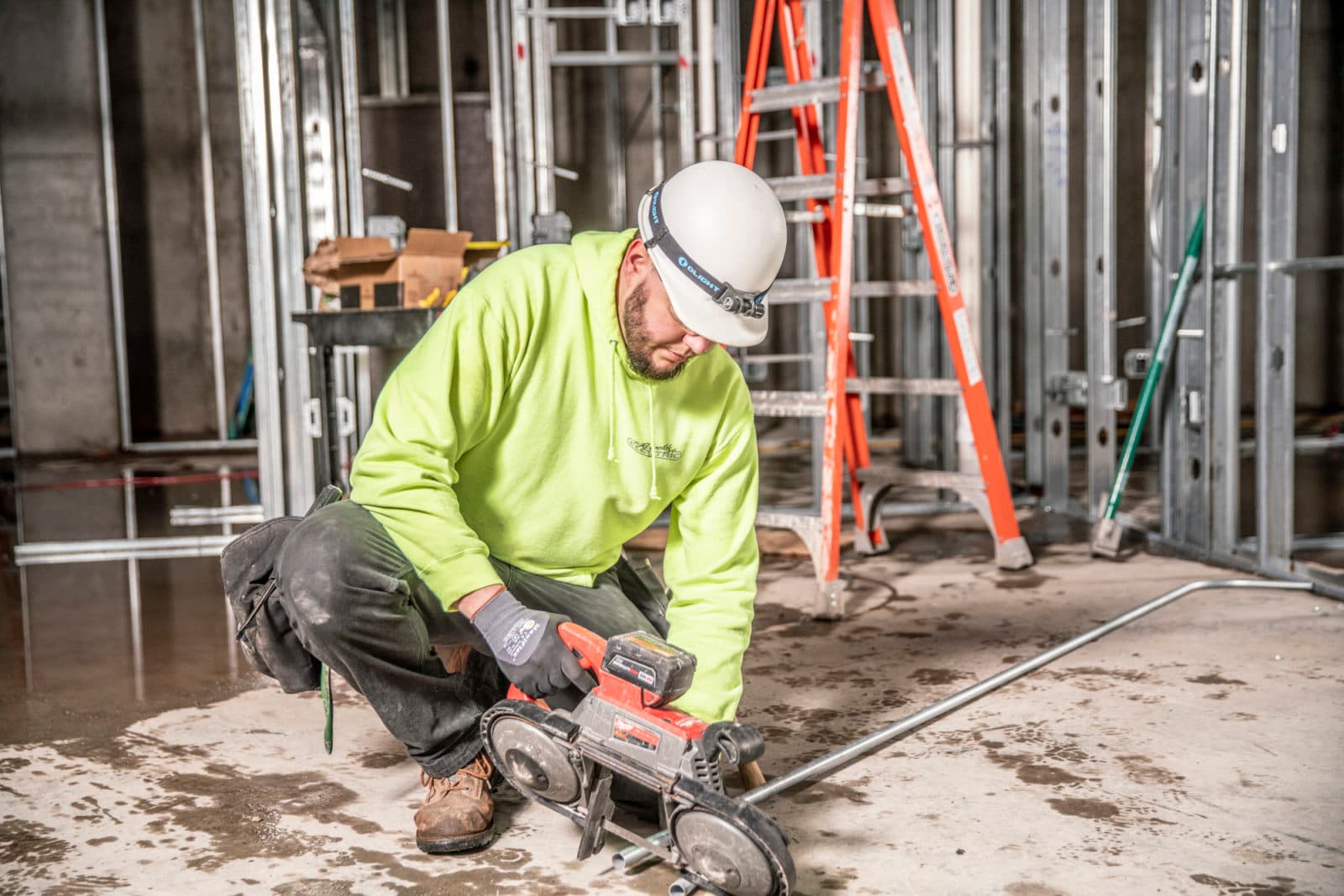 Worker cutting conduit with saw indoors