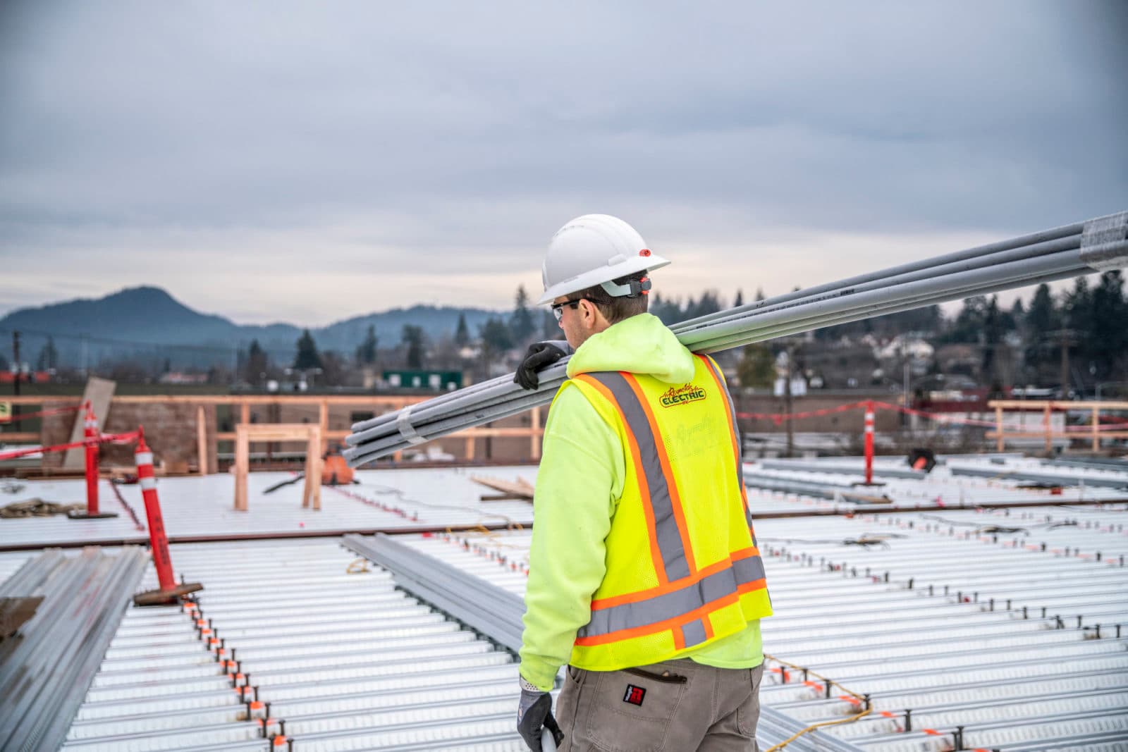 Worker carrying conduit across roof deck