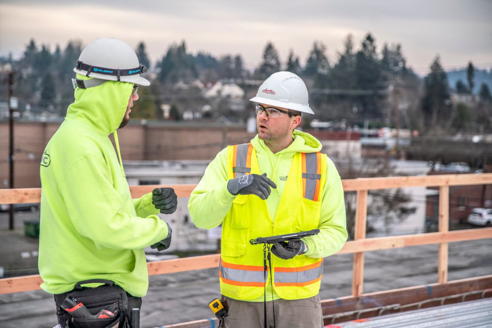 Two hi-vis workers talking on rooftop