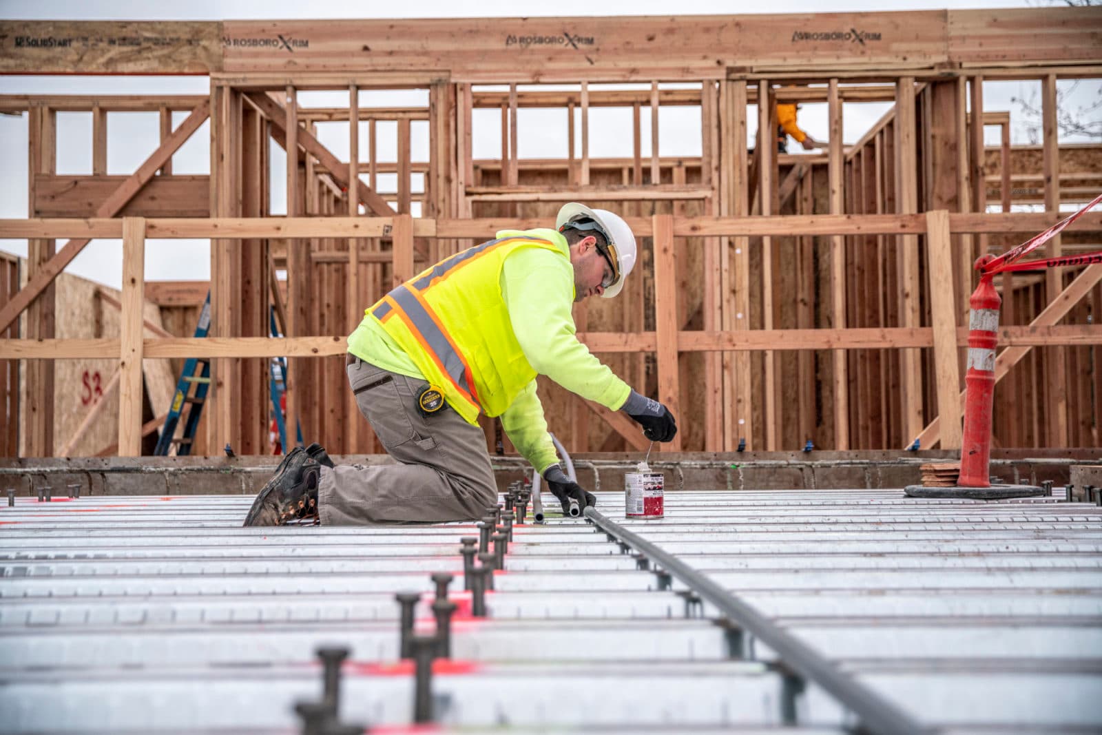 Worker marking floor deck in wood-framed building