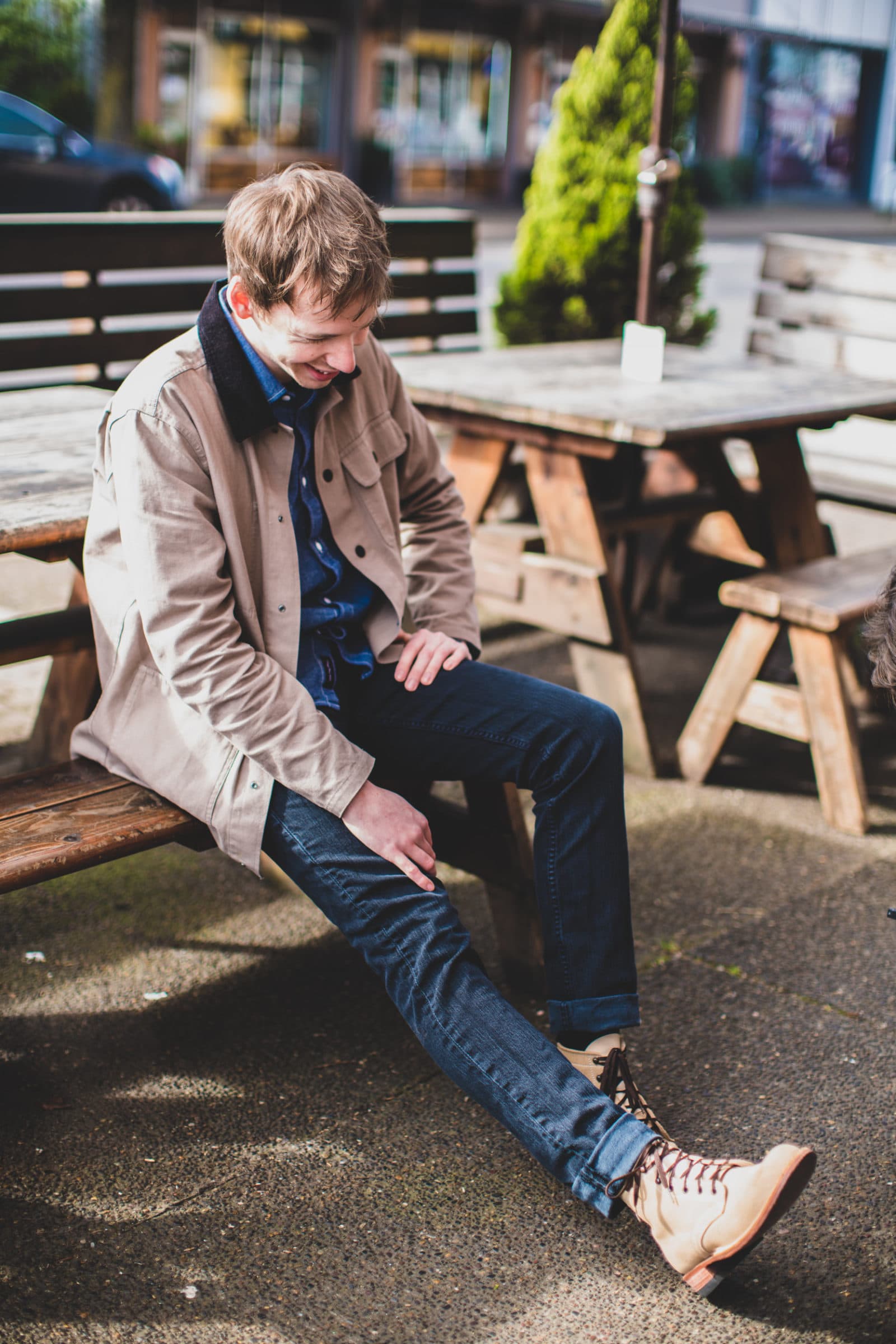 Young man sitting on picnic bench in boots