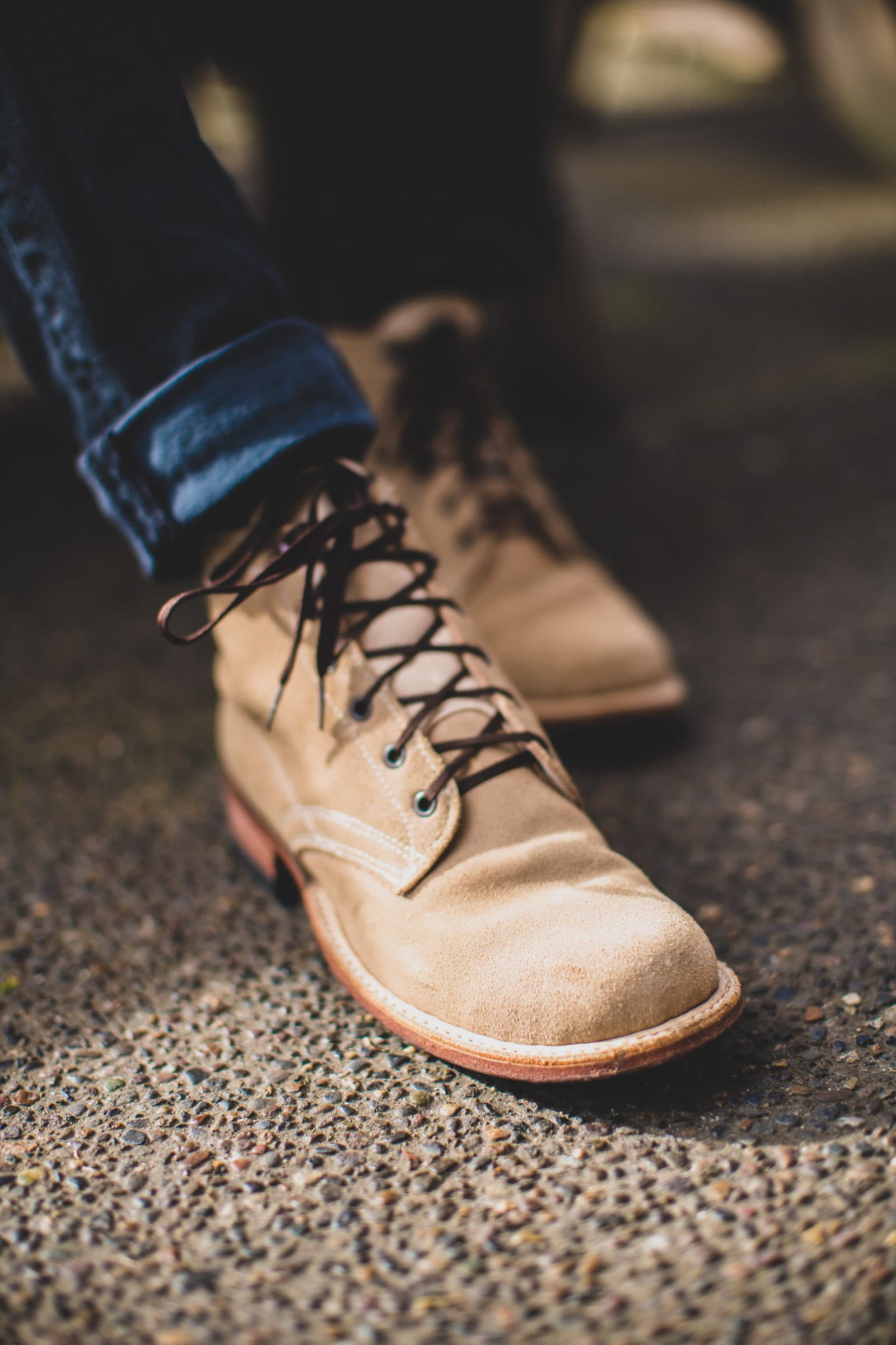 Tan suede boot stepping on pavement
