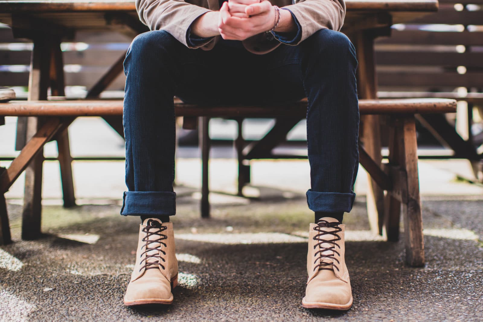 Seated man in tan boots at picnic table