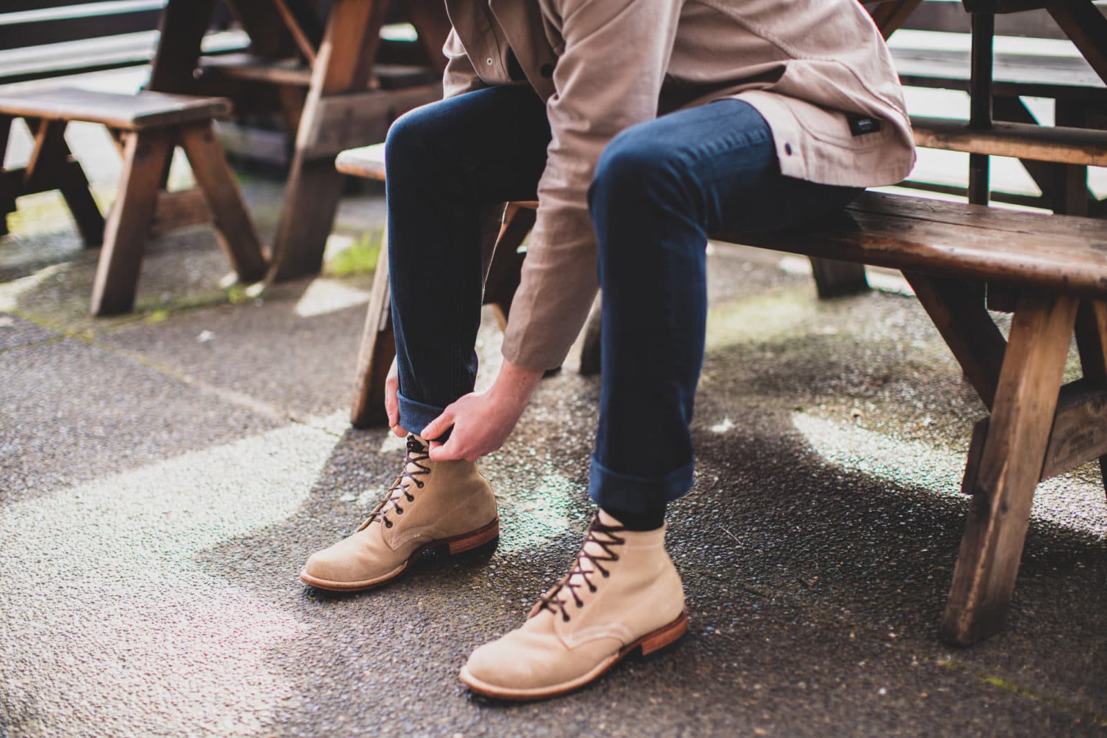 Man lacing tan boots at picnic table