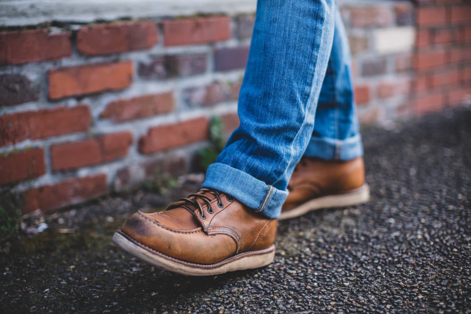 Brown moc-toe boots walking by brick wall