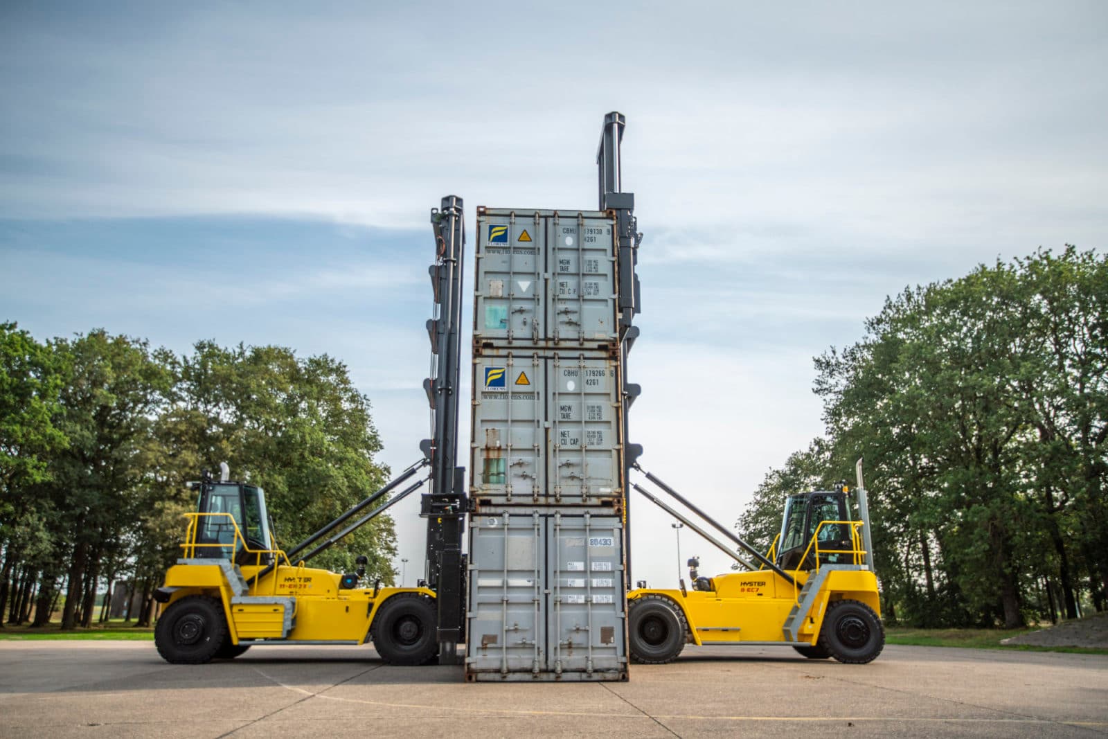 Two yellow Hyster container handlers lifting stack