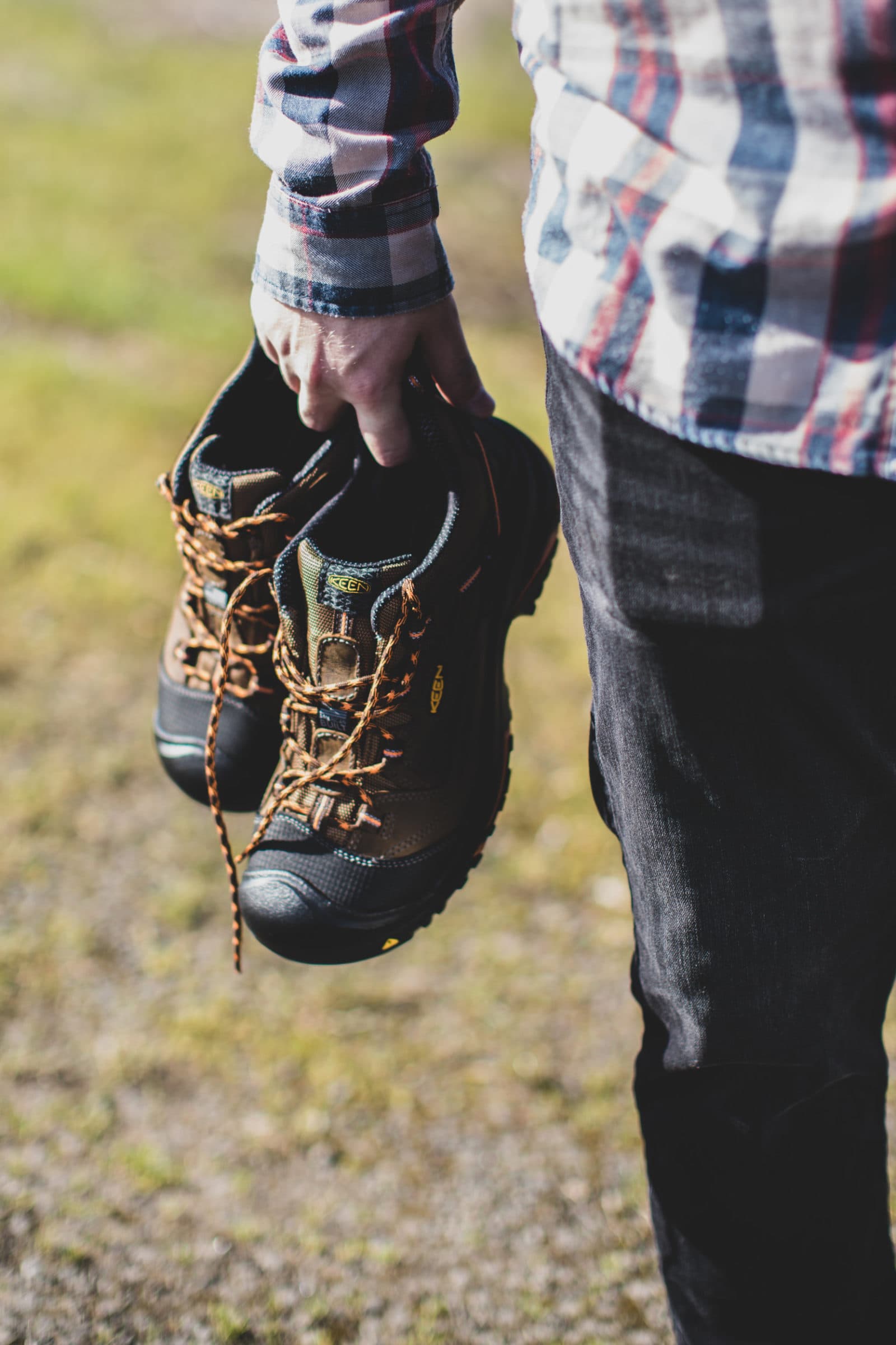 Hand carrying work boots by the laces