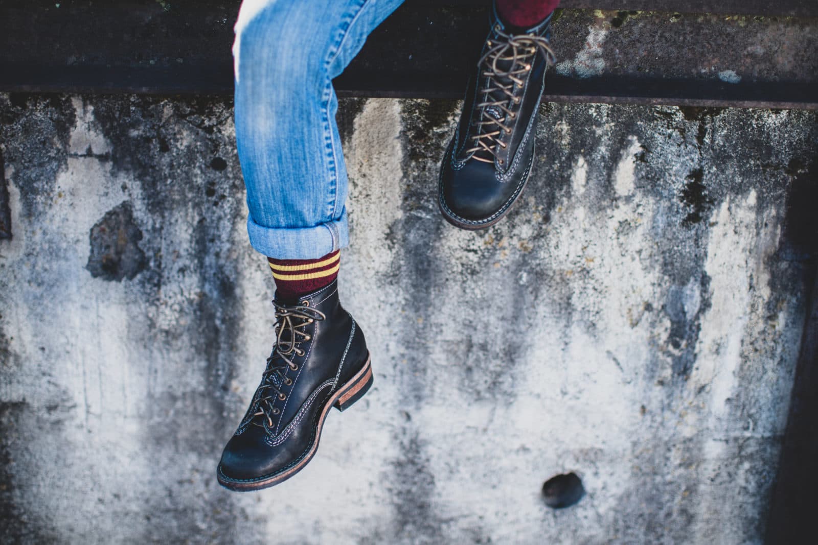 Black boots dangling over grungy wall
