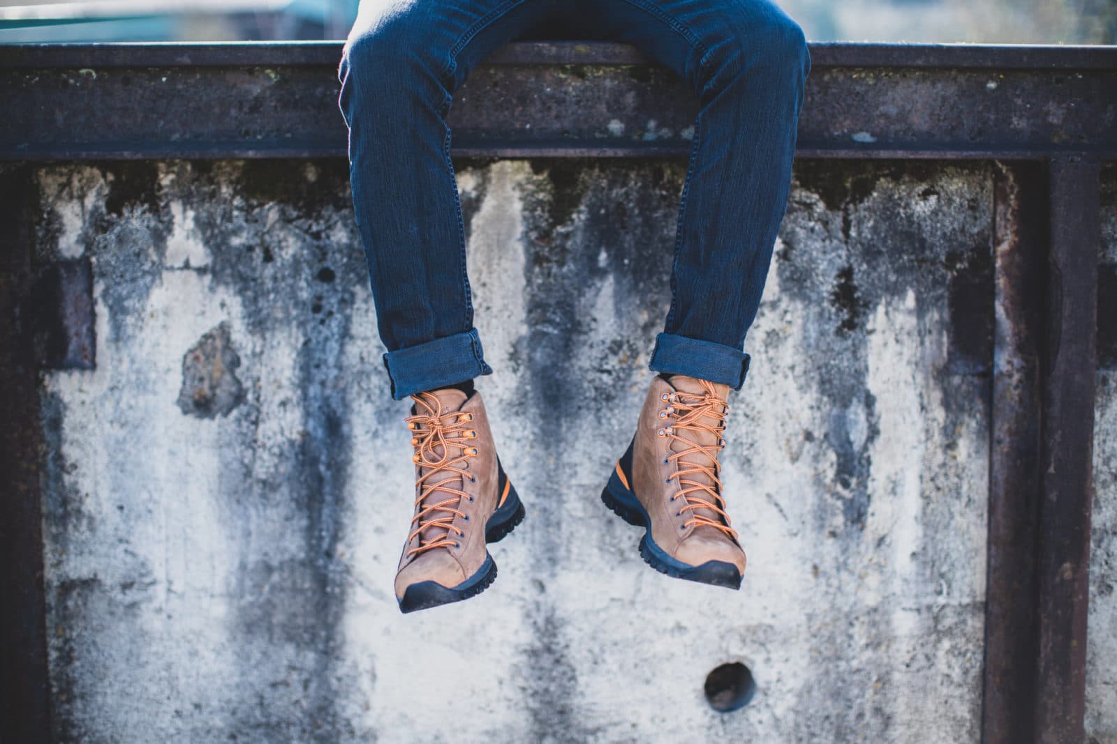 Boots dangling over weathered concrete wall