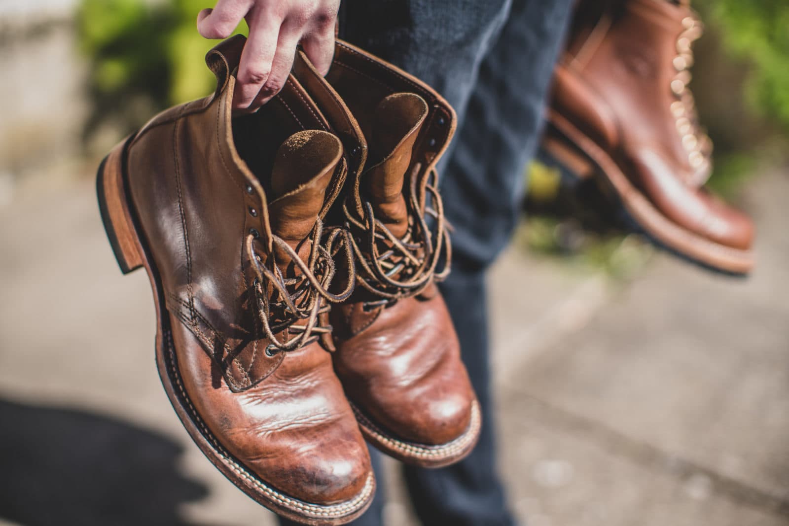 Hand holding brown leather lace-up boots