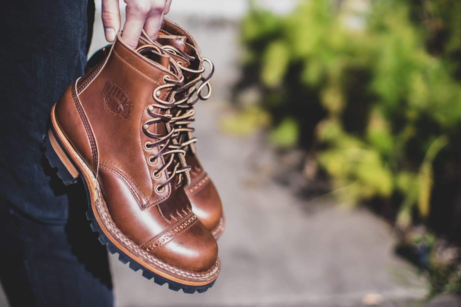 Hand holding brown lace-up leather boots