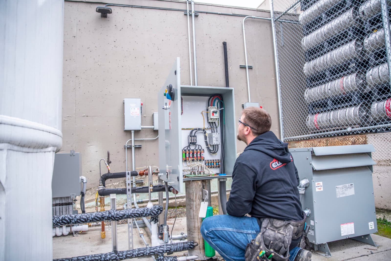 Electrician crouching by outdoor switchgear