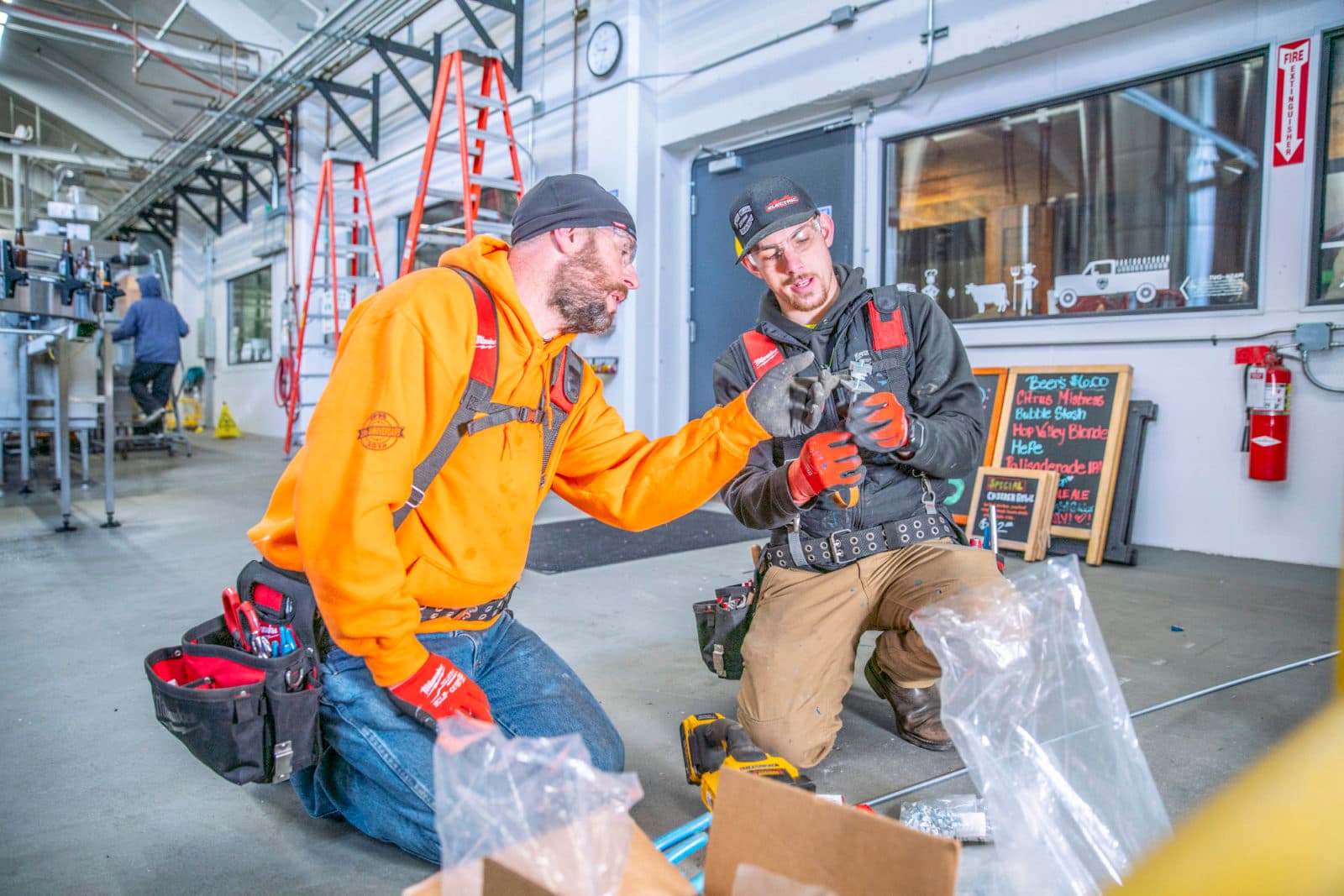 Two plumbers kneeling with parts in taproom