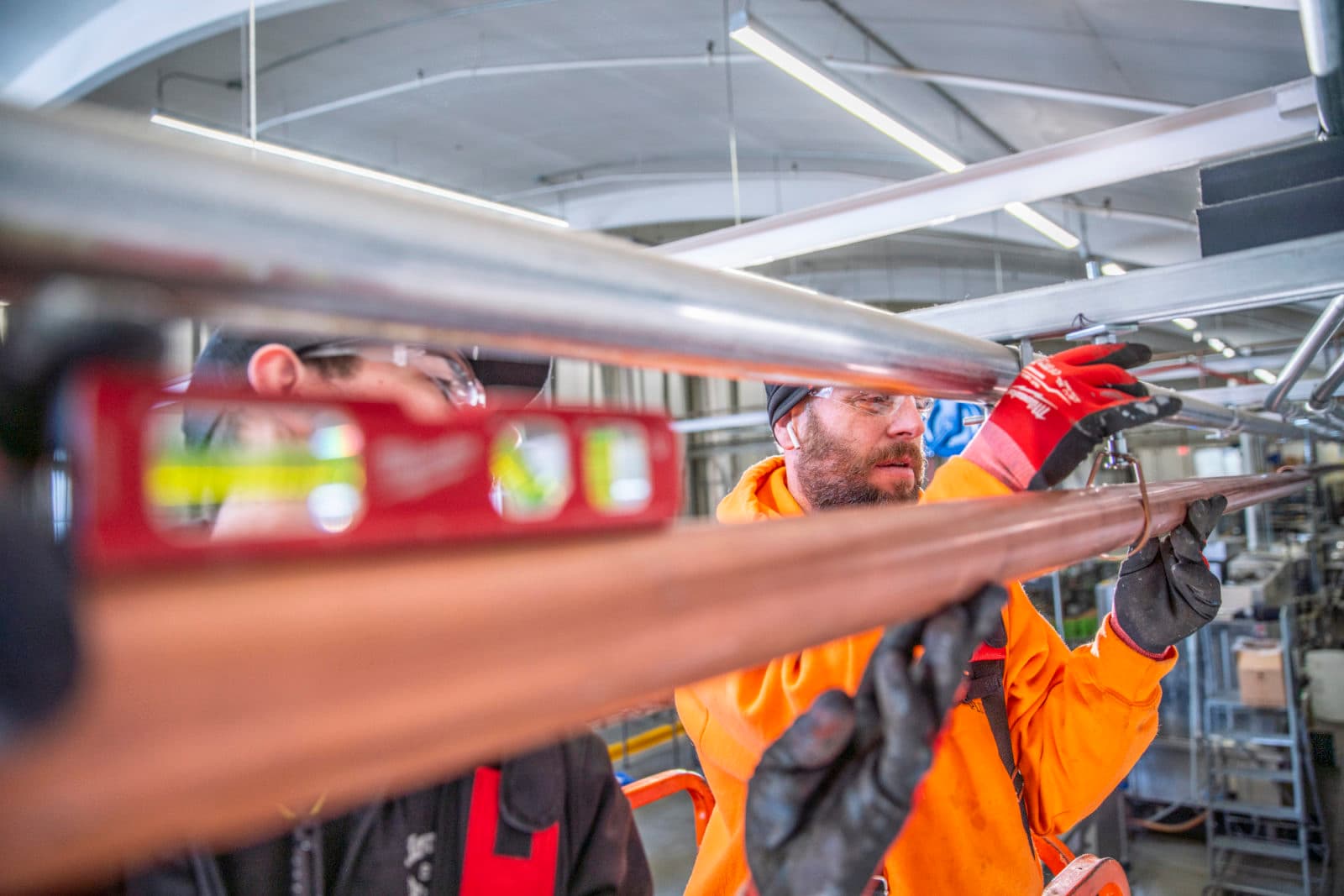 Plumbers leveling copper pipe overhead