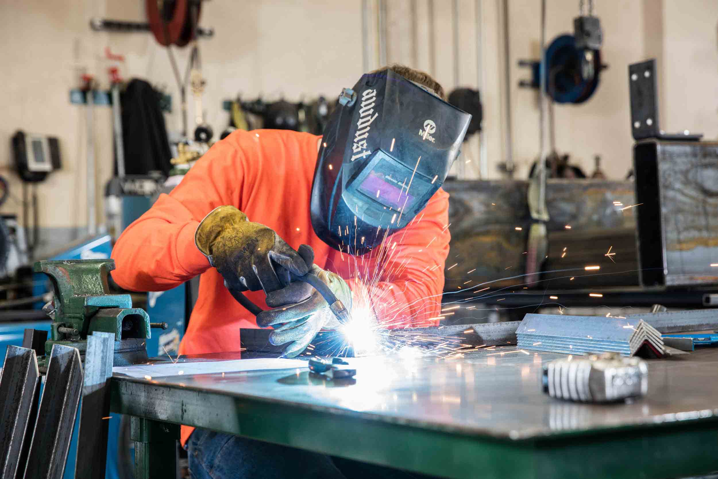 Welder in hi-vis welding at shop table