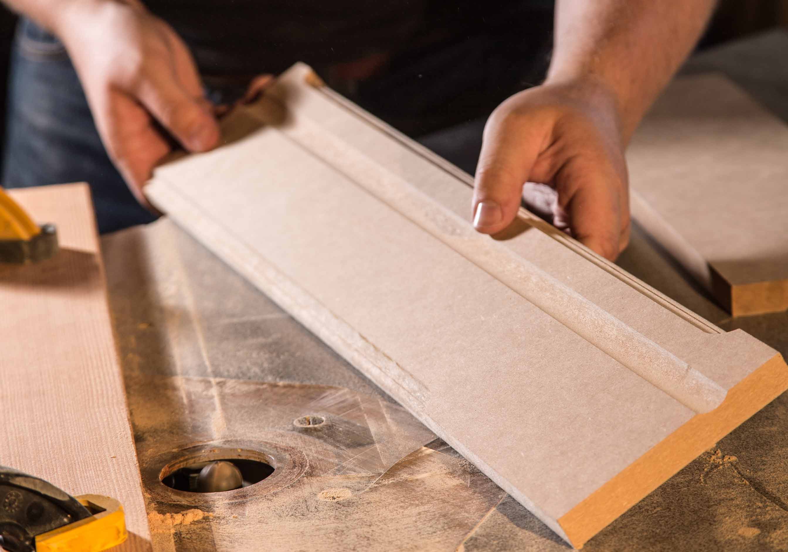 Hands shaping wood molding on router table