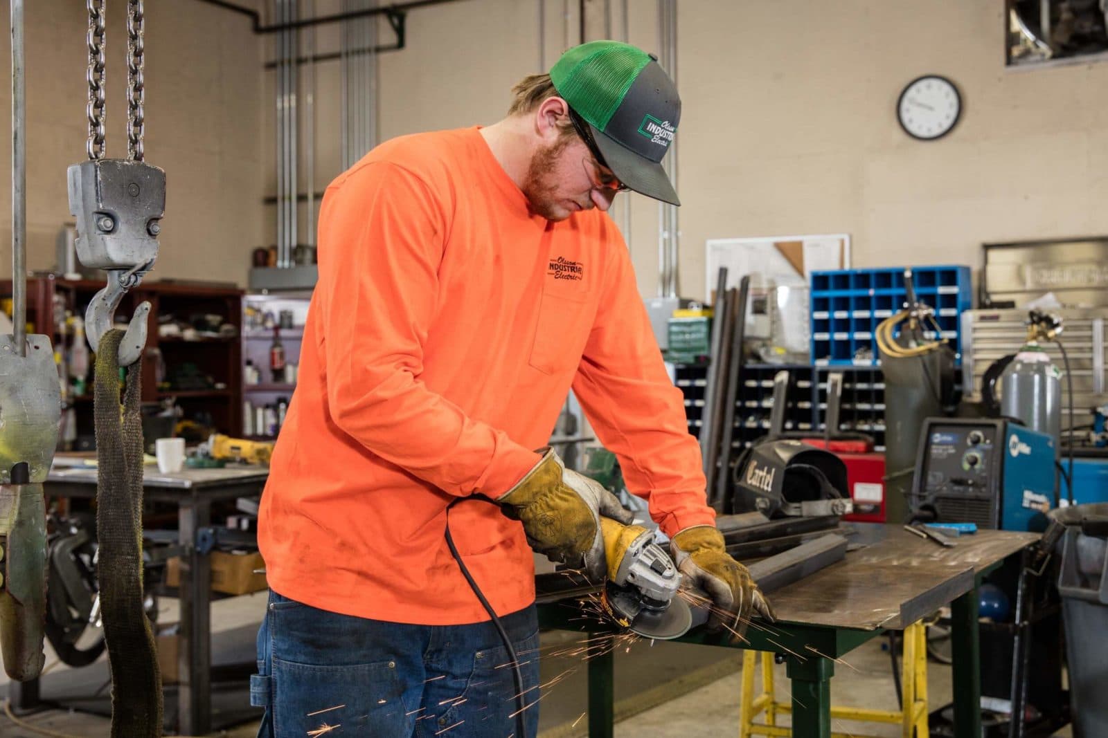 Fabricator grinding metal in orange shirt