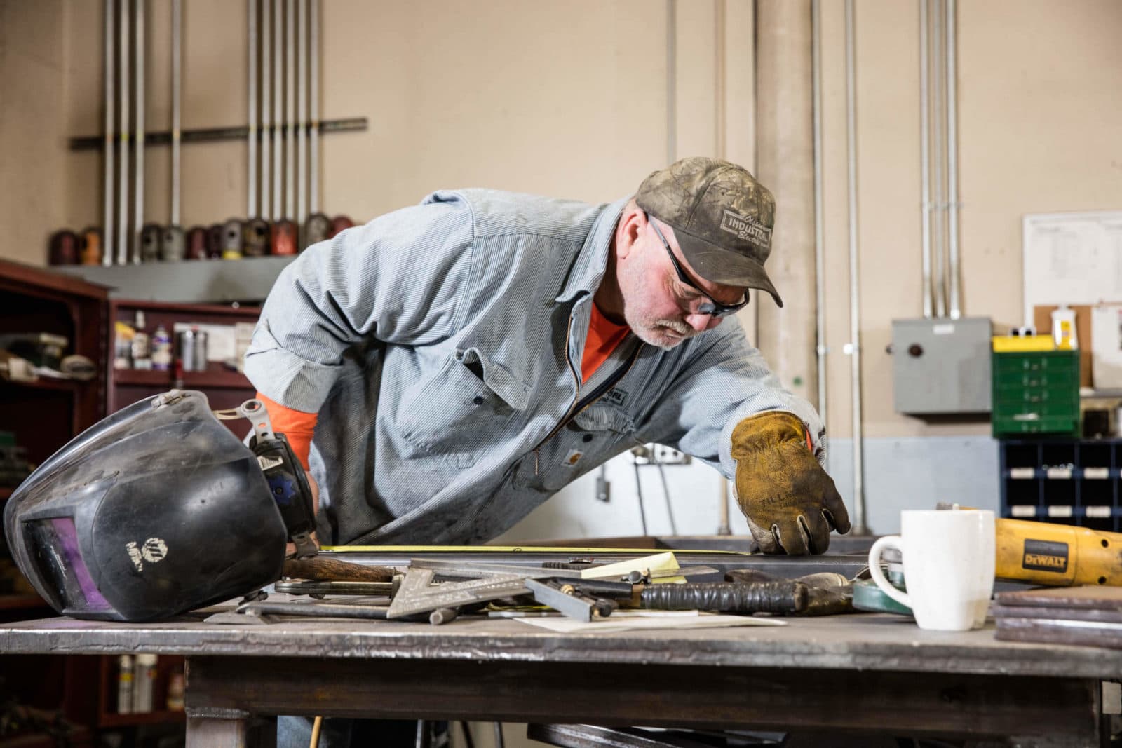 Fabricator measuring steel at workbench