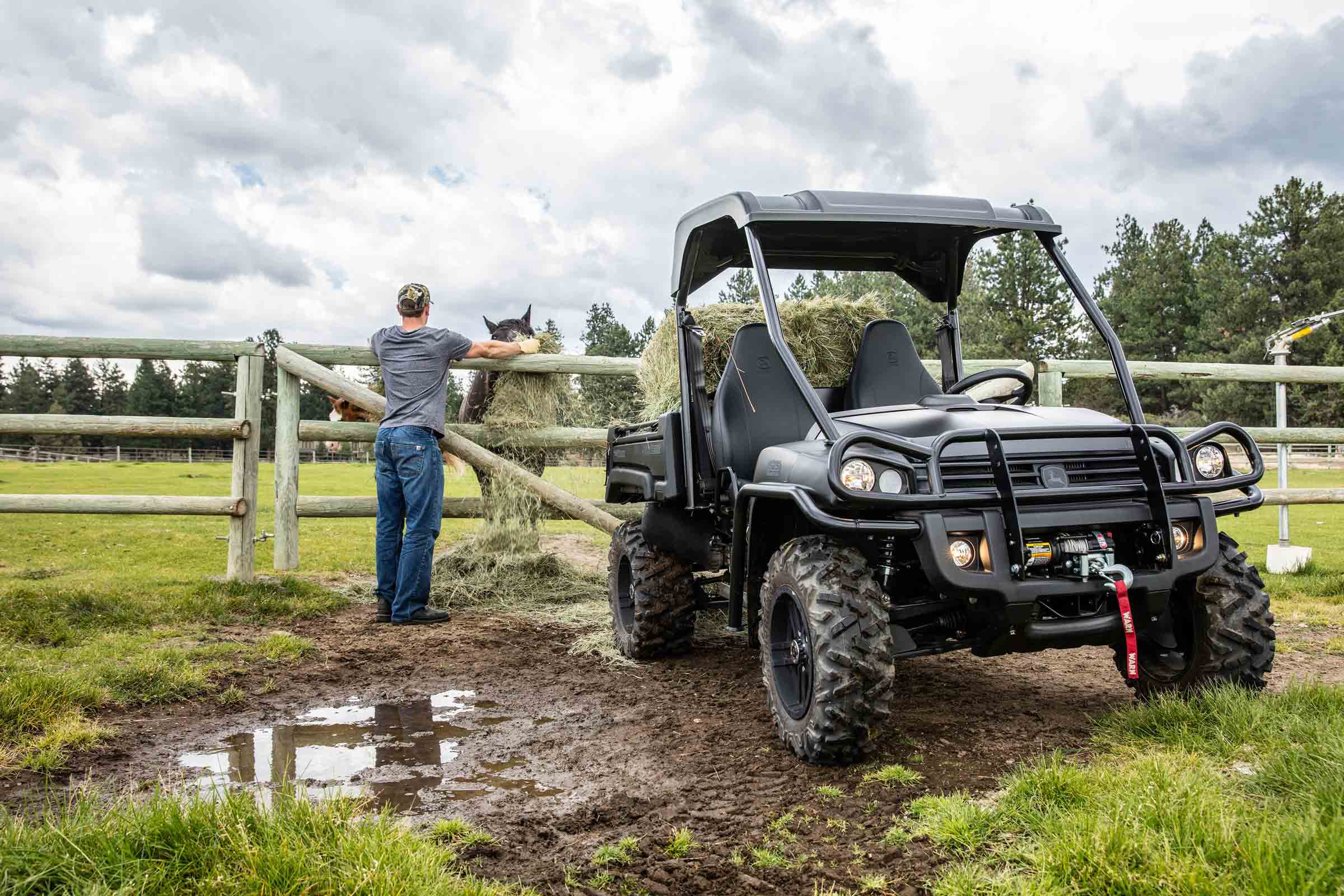 Rancher leaning on fence beside John Deere Gator