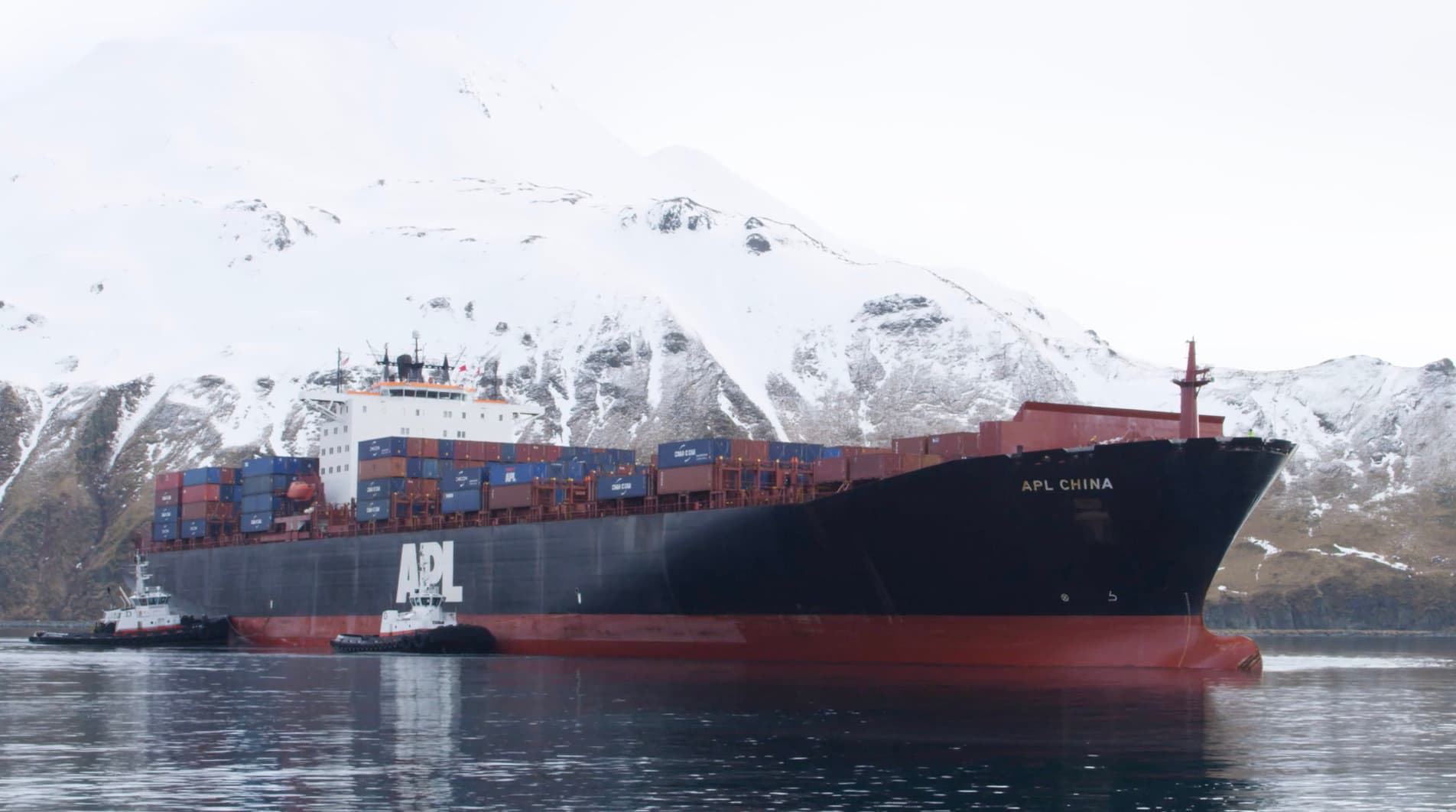 Container ship before snowy Alaska mountains