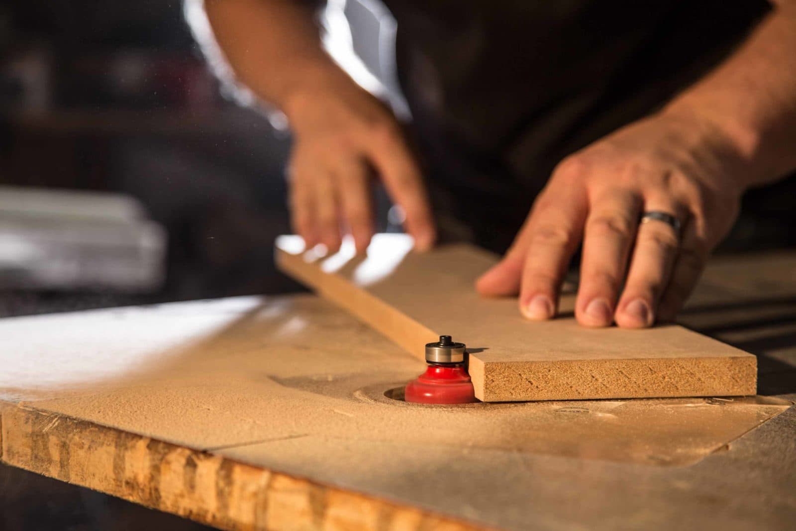 Hands routing wood edge on router table