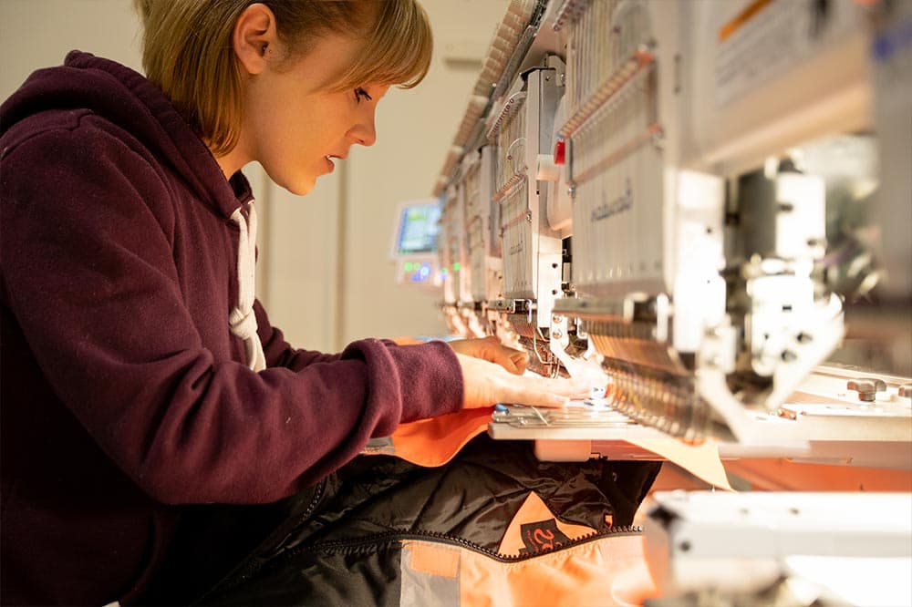 An FPW team member running a multi-head embroidery machine