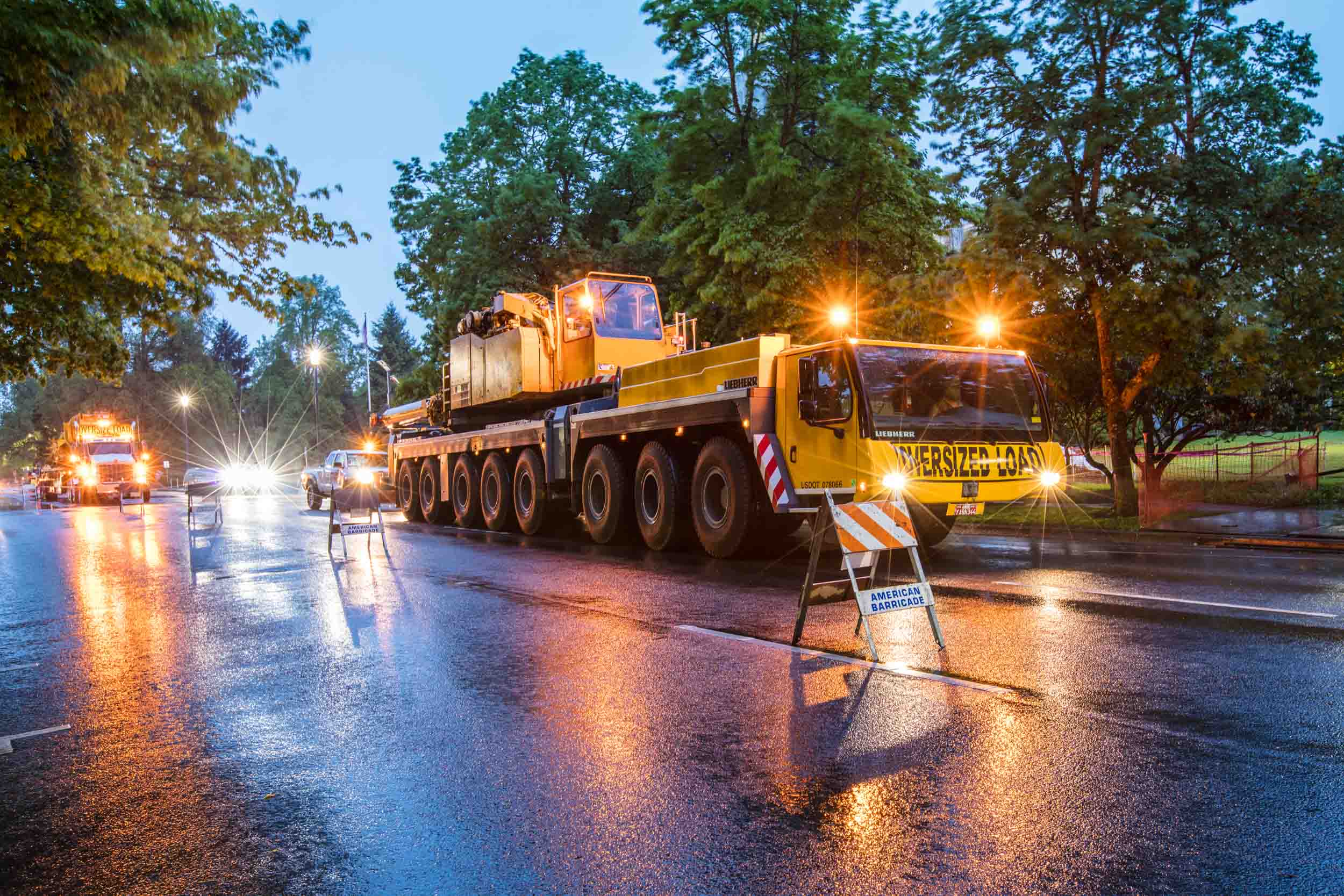 Heavy-haul crane convoy on wet street, dusk