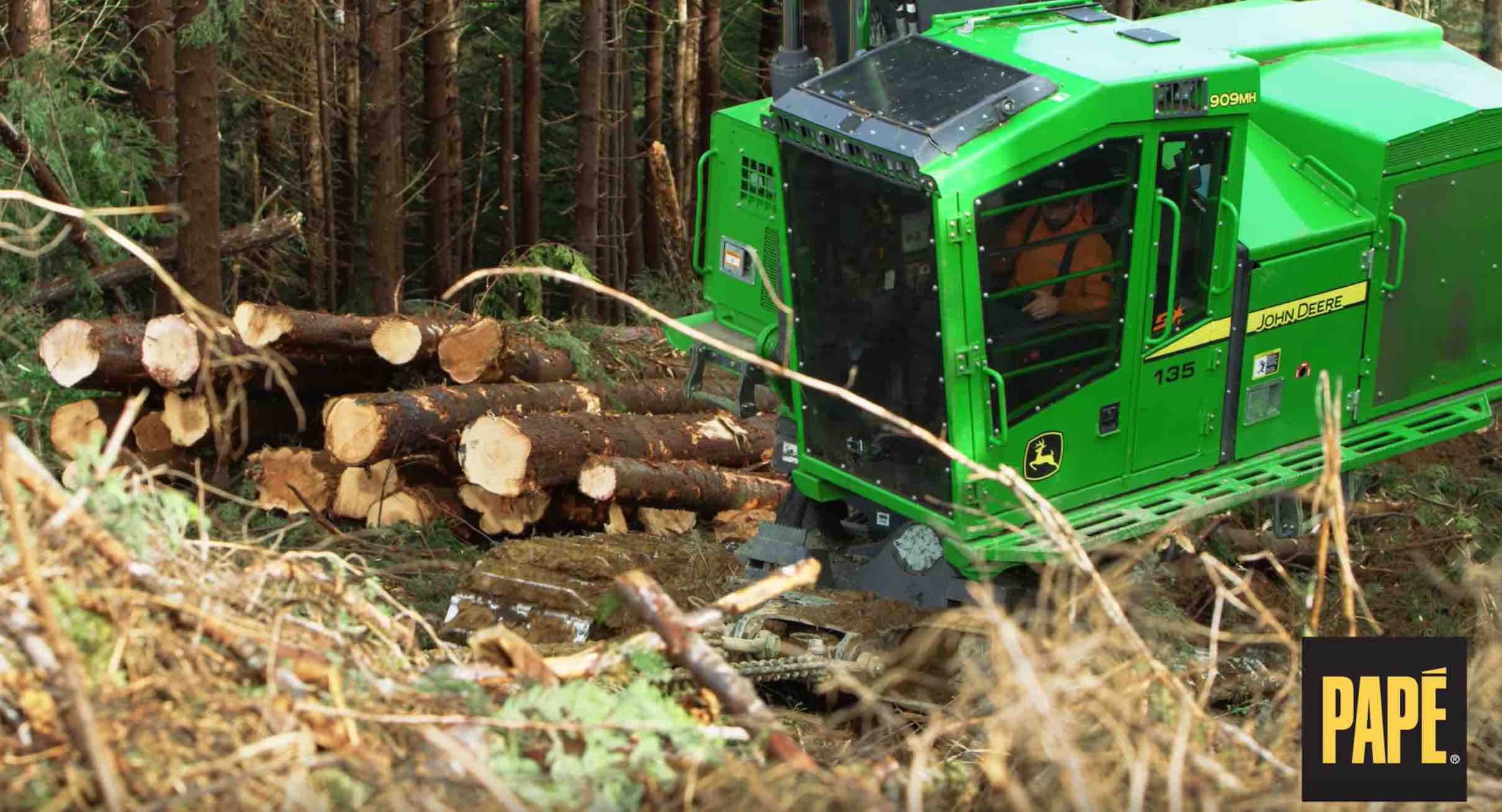 A green logging machine among cut logs, filmed from above